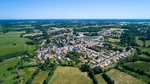 Luftaufnahme eines kleinen Dorfes, das in mitten grüner Felder liegt.