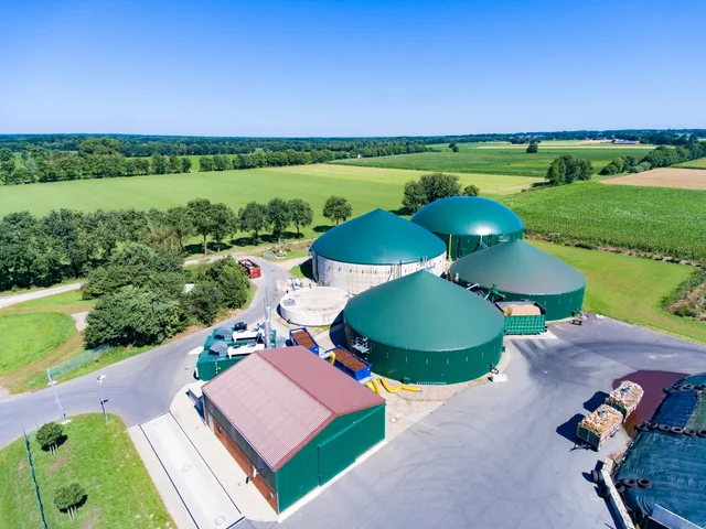 Luftaufnahme von einer modernen Biogasanlage mit grünen Feldern im Hintergrund.